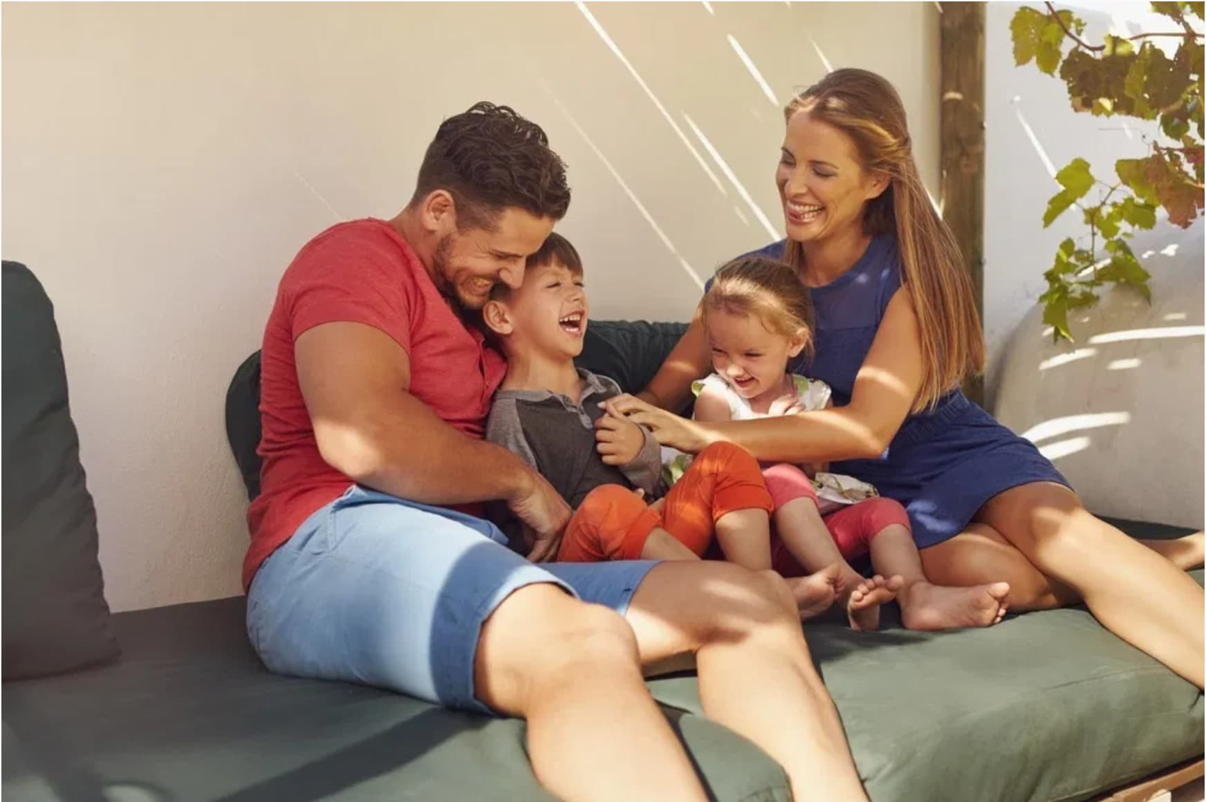 a happy family of four giggling on a couch